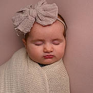 Giorgia is registered to the contest to win money with this photo: baby, sleeping, headband, bow, blanket, wrapped, portrait, closeup, infant, soft_lighting, studio, peaceful, cute, child, knit, pink_background, head, face, newborn, calm