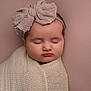 baby, sleeping, headband, bow, blanket, wrapped, portrait, closeup, infant, soft_lighting, studio, peaceful, cute, child, knit, pink_background, head, face, newborn, calm