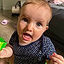 baby, child, indoor, polka_dot_clothing, blue_clothing, toy, floor, couch, home, furniture, curious, open_mouth, face, hand, sitting, expression, skin, head, eyes, person
