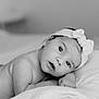 baby, infant, newborn, headband, bow, blanket, pillow, portrait, black_and_white, monochrome, eyes, gaze, face, skin, hand, lying_down, soft_texture, cute, adorable, peaceful