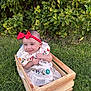 baby, child, smile, red_bow, headband, embroidered_dress, wooden_crate, grass, greenery, outdoor, happy, cute, sitting, nature, foliage, portrait, infant, playful, sunlight, garden