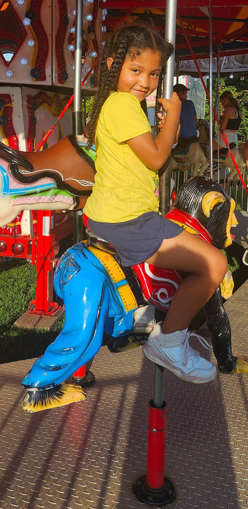 Rayne is registered to the contest to win money with this photo: amusement_park, amusement_ride, carousel, entertainment, event, fair, festival, fun, human_leg, joy, leisure, nonbuilding_structure, person, public_event, recreation, sandal, shoe, shorts, sneakers, t_shirt