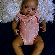 Zariah is registered to the contest to win money with this photo: baby, infant, child, onesie, heart_pattern, lace, pillow, fluffy, fabric, skin, face, eyes, hands, legs, feet, lying_down, portrait, indoor, cute, soft