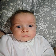 Noah is registered to the contest to win money with this photo: baby, bed, closeup, cozy, curious, expression, eyes, face, floral_pattern, head, indoors, infant, newborn, person, pillow, portrait, skin, soft_lighting, white_clothing, young_child