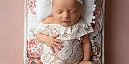 Novella is registered to the contest to win money with this photo: baby, bed, child, cushion, cute, floral, headband, indoors, infant, lace_clothing, newborn, peaceful, pillow, pink_background, portrait, resting, sleeping, soft_lighting, toddler, wooden_bed
