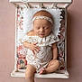 baby, bed, child, cushion, cute, floral, headband, indoors, infant, lace_clothing, newborn, peaceful, pillow, pink_background, portrait, resting, sleeping, soft_lighting, toddler, wooden_bed