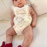 Emma joined the competition — help win amazing prizes! baby, infant, lace, red_bow, headband, socks, white_outfit, chubby_legs, lying_down, cute, portrait, soft_background, indoors, child, adorable, baby_clothes, smiling, closeup, face, person