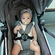 Inaya a rejoint le concours — aidez-le/la à gagner de superbes lots ! baby, pacifier, headband, stroller, seatbelt, infant, child, cute, indoor, clothing, person, babywearing, sitting, comfort, gray, soft, eyes, hand, footwear, portrait