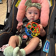 Addison is registered to the contest to win money with this photo: baby, car_seat, toy, headband, socks, indoor, floor, striped_fabric, pink, green, colorful_ball, child, infant, seatbelt, cute, person, toddler, face, expression, soft