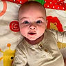 Everett is registered to the contest to win money with this photo: baby, background_pattern, beige_clothing, child, colorful, cute, expression, eyes, face, giraffe, indoors, infant, lion, lying_down, onesie, play_mat, portrait, skin, soft_toys, wooden_buttons