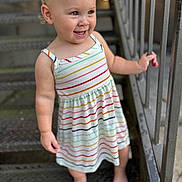Elisia joined the competition — help win amazing prizes! toddler, child, smiling, barefoot, striped_dress, metal_stairs, railing, outdoor, curly_hair, happy, person, portrait, feet, hand, clothing, standing, playful, cute, young_child, daylight