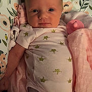 Reagan is registered to the contest to win money with this photo: baby, infant, blanket, pacifier, onesie, crown_pattern, pink, white_clothing, face, skin, hand, arm, indoor, soft_lighting, newborn, cute, lying_down, fabric, child, portrait
