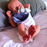 Noah is registered to the contest to win money with this photo: baby, sleeping, pacifier, pillow, bed, white_sheet, infant, newborn, feet, hands, clothing, blanket, peaceful, cute, indoors, person, resting, soft_light, closeup, relaxation
