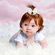 Averie is registered to the contest to win money with this photo: baby, child, portrait, red_hair, bow, hair_accessory, blue_eyes, smiling, indoor, fluffy_blanket, white_background, pastel_background, sitting, lying_down, overalls, white_shirt, infant, face, photography, cute