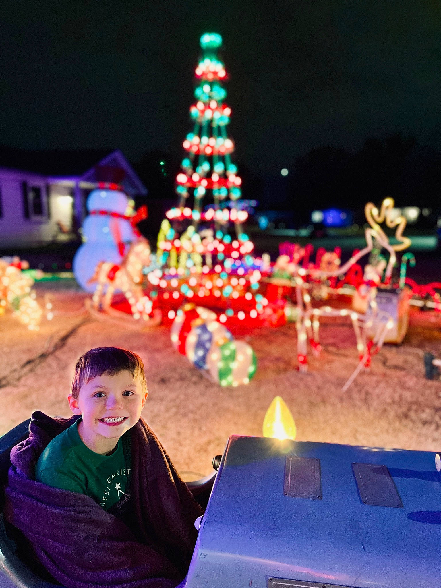 Malik is registered to the contest to win money with this photo: beauty, christmas, christmas_decoration, christmas_eve, christmas_ornament, christmas_tree, event, fun, happy, holiday, joy, lap, leisure, light, midnight, person, public_space, sky, toddler, travel