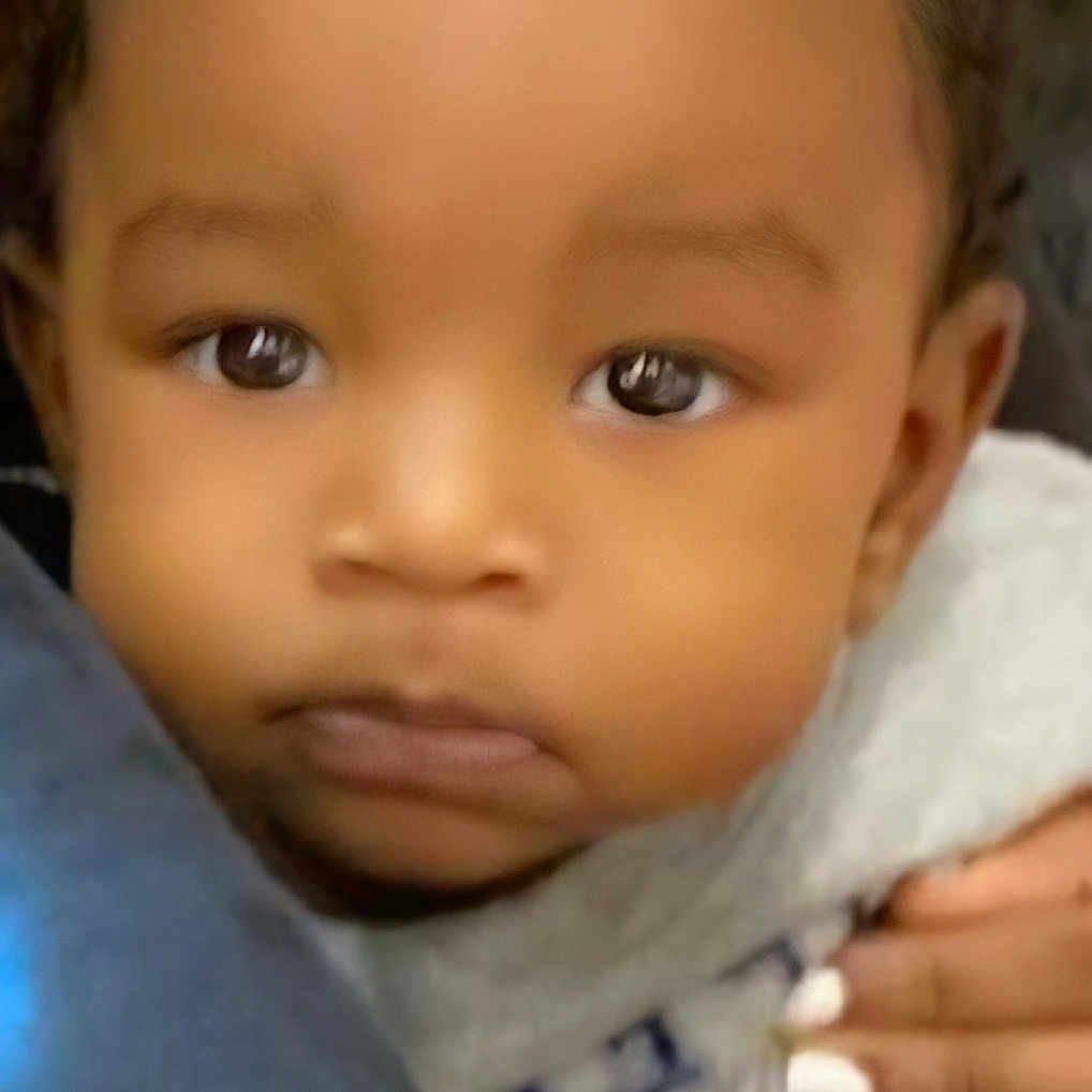 Akaiyo Keomani Knox is registered to the contest to win money with this photo: adorable, baby, child, close_up, clothing, cozy, cute, expression, eyes, face, hand, holding, indoors, infant, looking, person, portrait, skin, soft, young