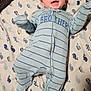 baby, infant, smiling, onesie, striped_clothing, blue_clothing, blanket, whale_pattern, happy, lying_down, face, arm_movement, footed_pajamas, cute, child, cheerful, indoor, soft_texture, fabric, sleepwear