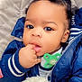 baby, child, cute, curly_hair, blue_jacket, blanket, pacifier, hand, face, portrait, indoors, closeup, infant, warm_clothing, soft_texture, cozy, young_child, expression, skin, person