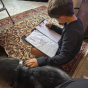 Doc joined the competition — help win amazing prizes! child, dog, drawing, sketchbook, carpet, indoor, hand, petting, furniture, sitting, hair, sleeve, collar, notebook, peace_sign, photo_frame, table_leg, floor, relaxation, home