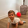 Edgar participe au concours pour gagner de l'argent avec cette photo : child, baby, toddler, crawling, onesie, striped_sock, red_balloon, white_balloon, hardwood_floor, potted_plant, clay_pot, indoor, white_wall, big_eyes, brown_hair, hands, curious_expression, portrait, playtime, flooring