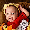 baby, child, smiling, hat, red_clothing, yellow_hat, plush_toy, basket, cozy, cute, portrait, indoors, happy, infant, face, headwear, soft_toy, toddler, warm, closeup