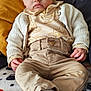 Noah participe au concours pour gagner de l'argent avec cette photo : baby, infant, child, blue_eyes, beige_clothing, knitted_cardigan, patterned_shirt, pants, socks, blanket, cushion, indoor, portrait, cute, serious_expression, sitting, relaxed, soft_lighting, cozy, closeup