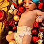 baby, blanket, celebration, child, christmas_ornaments, colorful, cute, decorations, diaper, festive, holiday, holiday_season, indoors, infant, playful, portrait, red_hat, relaxing, smiling, soft_texture