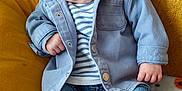 Noah a rejoint le concours — aidez-le/la à gagner de superbes lots ! baby, child, blue_hat, mickey_mouse_patch, denim_jacket, striped_shirt, jeans, white_shoes, blanket, pumpkin_pattern, black_cat_pattern, couch, yellow_couch, seated, indoors, cute, portrait, cozy, fall_theme, casual_clothing
