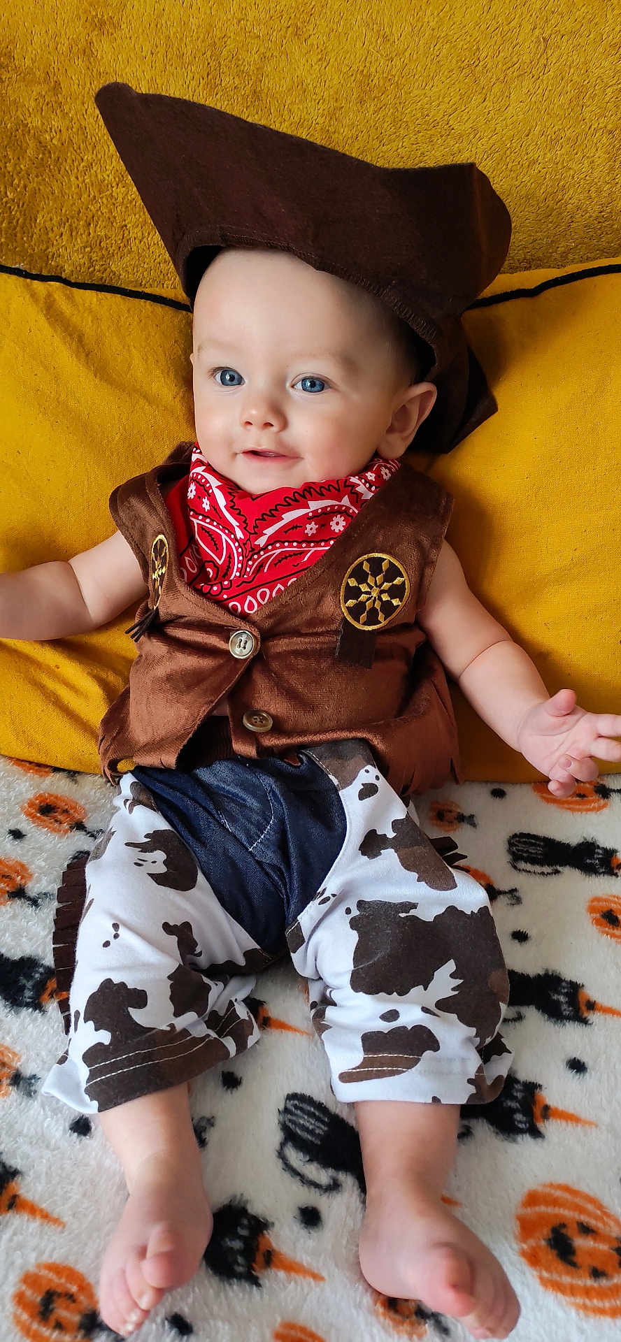 Noah a rejoint le concours — aidez-le/la à gagner de superbes lots ! baby, cowboy_costume, hat, bandana, pants, cow_print, blanket, halloween, pumpkin, black_cat, orange, white, brown, blue_eyes, smiling, infant, clothing, foot, cute, portrait