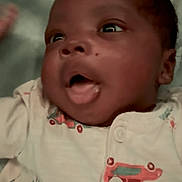 Leviticus is registered to the contest to win money with this photo: baby, infant, close_up, face, expression, onesie, clothing, blanket, lying_down, cute, child, newborn, soft, portrait, skin, head, mouth_open, eyes, hand, indoor