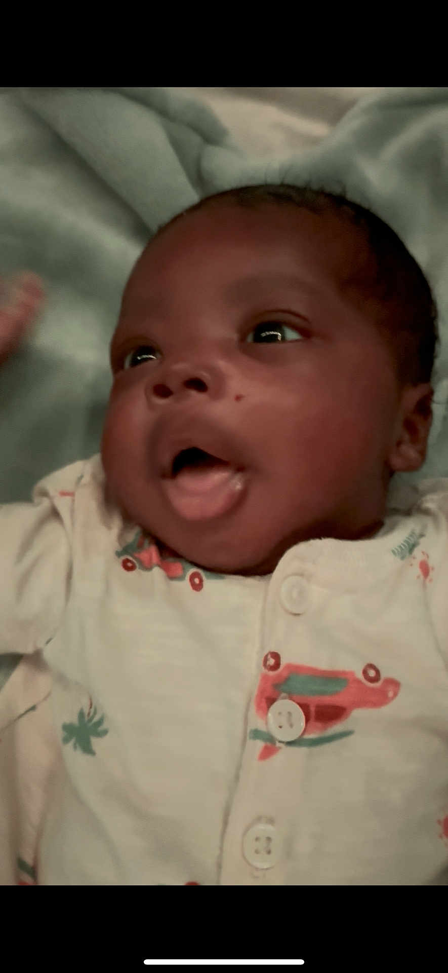 Leviticus is registered to the contest to win money with this photo: baby, infant, close_up, face, expression, onesie, clothing, blanket, lying_down, cute, child, newborn, soft, portrait, skin, head, mouth_open, eyes, hand, indoor