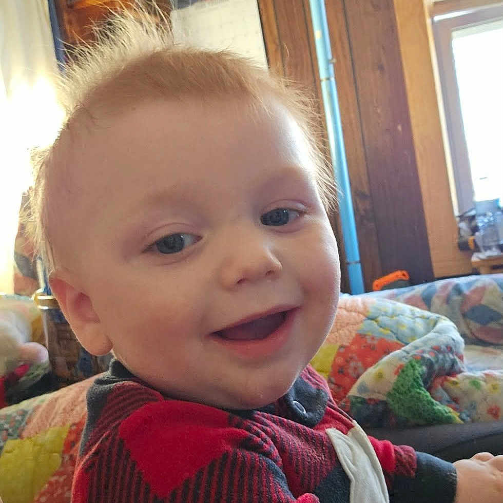 Braxley joined the competition — help win amazing prizes! blonde_hair, casual, checkered_pattern, child, cozy, cute, face, happy, home, indoor, lamp, person, portrait, quilt, red_clothing, smiling, toddler, warm_lighting, window, wooden_wall