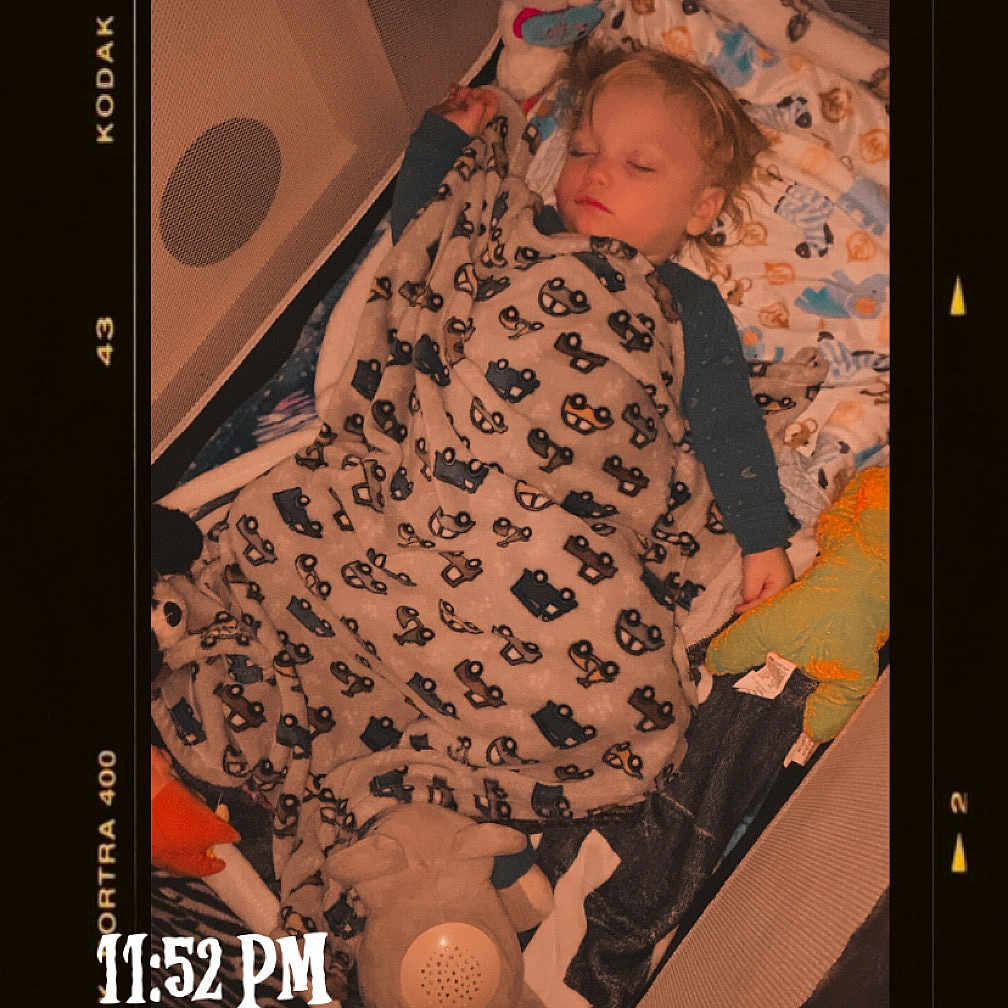 Braxley is registered to the contest to win money with this photo: toddler, sleeping, blanket, plush_toy, bed, child, indoors, cozy, nap, soft_lighting, pattern, comfort, cute, peaceful, portrait, rest, young_child, sleepwear, toy, warm_tone