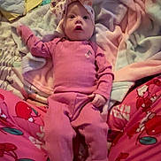 Evelynn joined the competition — help win amazing prizes! baby, infant, newborn, headband, bow, onesie, pink_clothing, socks, blanket, bed, pajamas, cherry_pattern, looking_up, wide_eyes, parent_legs, pacifier, cozy, soft_fabric, portrait, indoor