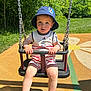 bucket_hat, child, daylight, footwear, grass, hat, holding, leisure, nature, outdoor, park, play, playground, romper, sandals, summer, sunny, swing, toddler, trees