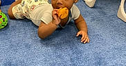 Roy is registered to the contest to win money with this photo: baby, baby_gear, blue_carpet, carpet, child, clothing, colorful, crawling, curious, floor, furniture, indoor, orange_toy, play_area, playtime, shorts, toddler, toy, white_shirt, young_child
