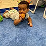 Roy is registered to the contest to win money with this photo: toddler, child, blue_carpet, toy, orange_toy, crawling, indoor, play_area, baby_gear, curious, floor, clothing, shorts, white_shirt, baby, playtime, colorful, carpet, furniture, young_child
