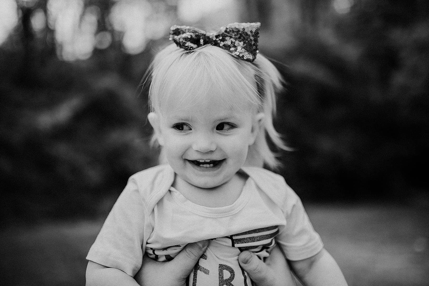 Delaney is registered to the contest to win money with this photo: baby, black, black_and_white, clothing, eye, face, flash_photography, grass, hair, happy, head, iris, joy, monochrome, person, skin, smile, standing, style, sunlight