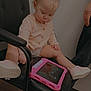 Lana joined the competition — help win amazing prizes! toddler, child, tablet, pink_case, chair, black_chair, indoor, wooden_floor, peach_cardigan, pigtails, pink_shoes, curious, sitting, person, hand, foot, technology, playing, young_child, neutral_wall