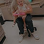 toddler, child, man, tablet, indoor, clinic, cabinet, floor, shoes, pigtails, smile, holding, seated, sanitizer, countertop, casual_clothing, white_shoes, black_pants, light_skin, happy