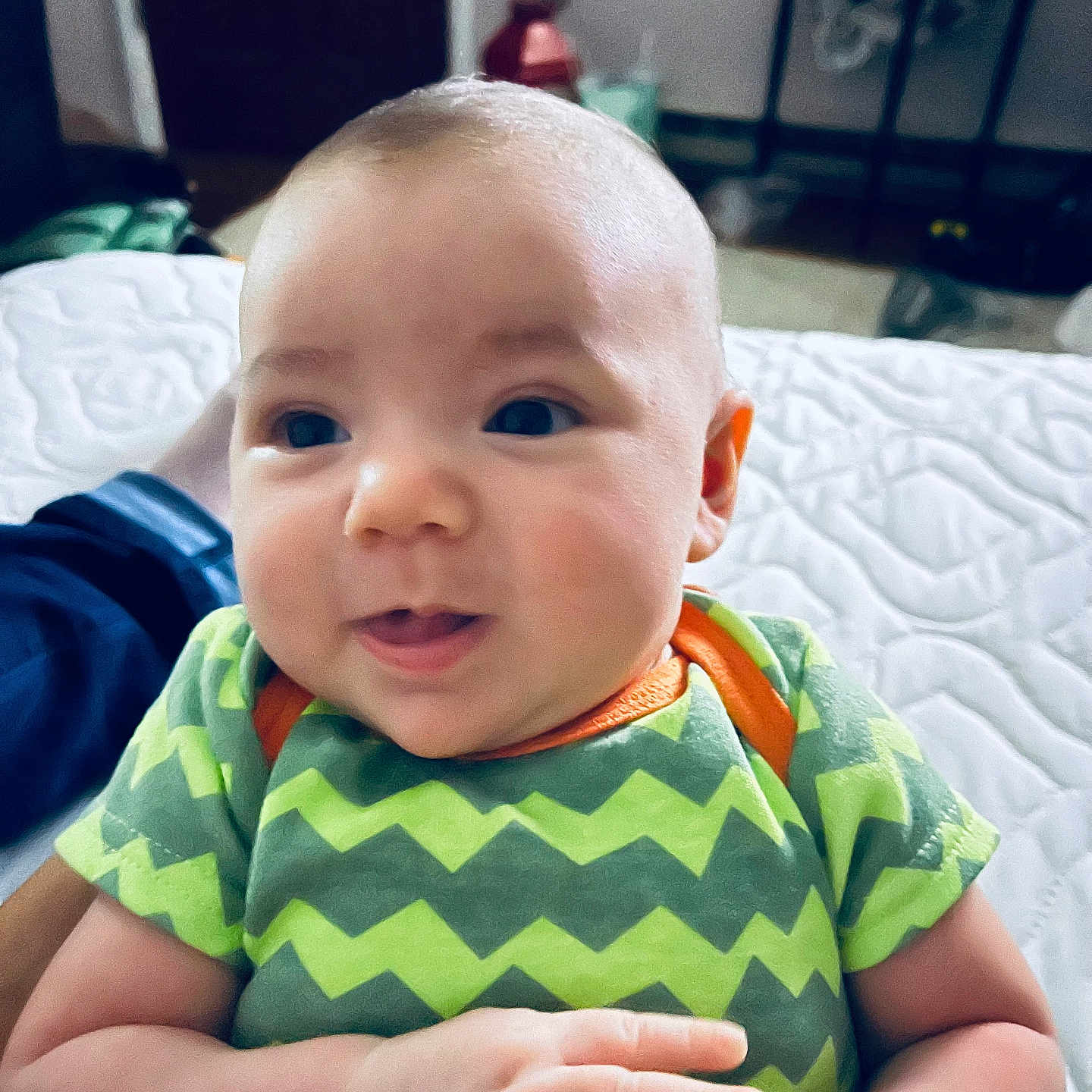 Kyle joined the competition — help win amazing prizes! baby, bed, bedroom, bodypart, clothing, face, finger, furniture, hand, happy, head, indoors, newborn, person, photography, portrait, room, sitting, smile, t_shirt