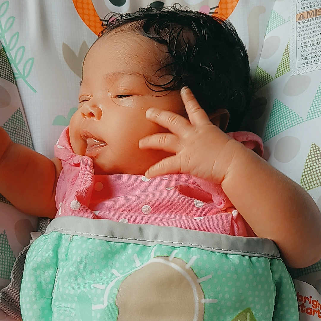 Journey is registered to the contest to win money with this photo: baby, baby_seat, child, comfort, curly_hair, cute, fabric, hand, indoors, infant, leaf_pattern, lion_pattern, newborn, pink_clothing, polka_dot, portrait, resting, sleepy, small_child, soft_light