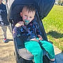 toddler, child, stroller, pacifier, outdoor, sunny, green_pants, dinosaur_pajamas, sidewalk, grass, person, walking, blue_sky, shoes, jacket, happy, daytime, casual_clothing, baby, family