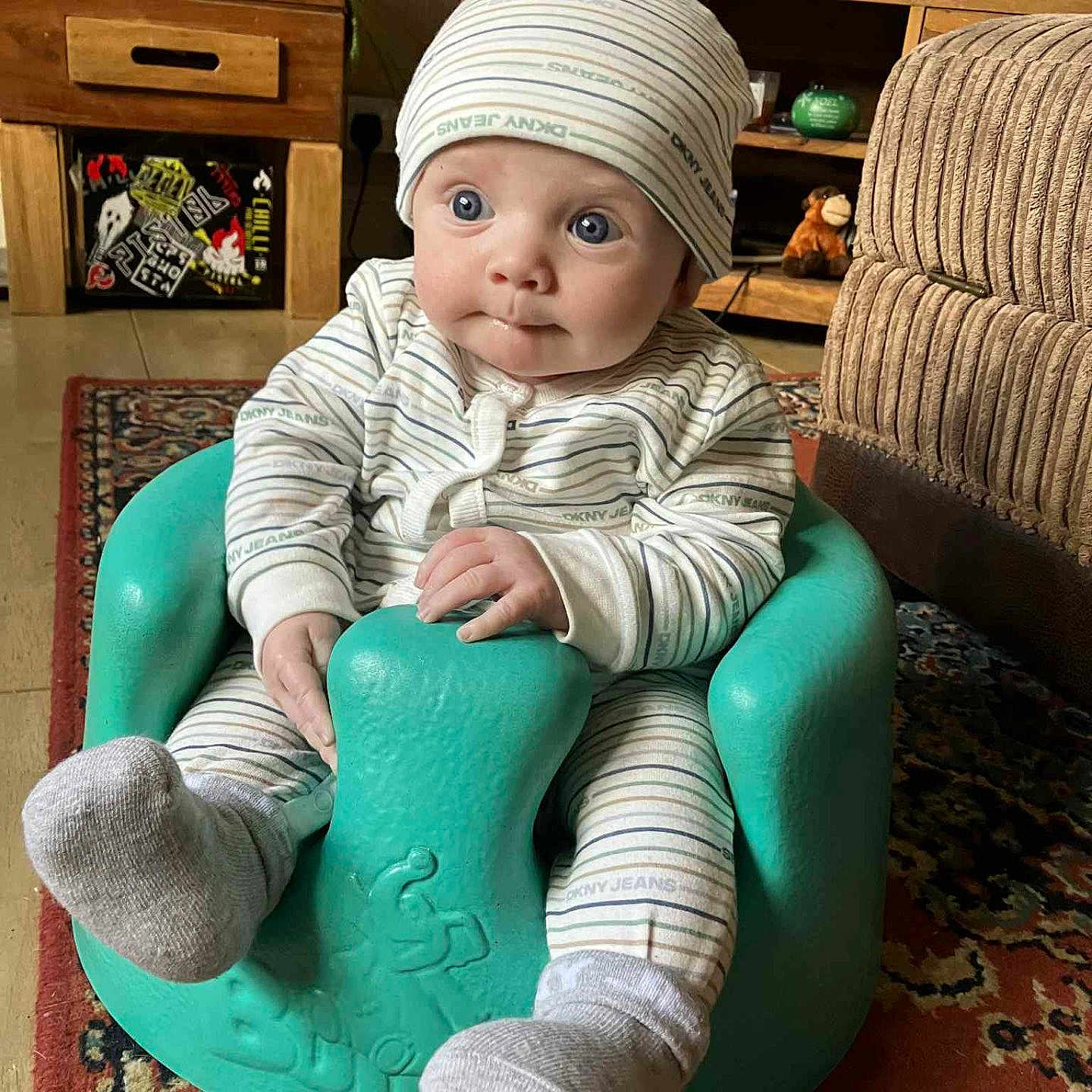 Caleb James joined the competition — help win amazing prizes! baby, blue_eyes, carpet, child, cozy, curious, decorations, face, hands, hat, indoors, infant, living_room, pajamas, portrait, sitting, sock, striped_clothing, turquoise_seat, wooden_furniture