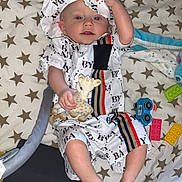 Raphaël participe au concours pour gagner de l'argent avec cette photo : baby, blanket, child, clothing, colorful_toys, comfort, cute, fabric, foot, giraffe_toy, hand, hat, indoor, infant, person, playing, resting, star_pattern, toy, young_child
