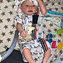 baby, blanket, child, clothing, colorful_toys, comfort, cute, fabric, foot, giraffe_toy, hand, hat, indoor, infant, person, playing, resting, star_pattern, toy, young_child