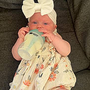 Aaliyah joined the competition — help win amazing prizes! baby, infant, bottle, milk, headband, bow, dress, floral, couch, fabric, cute, child, sitting, indoors, skin, person, feeding, comfort, young, relaxing