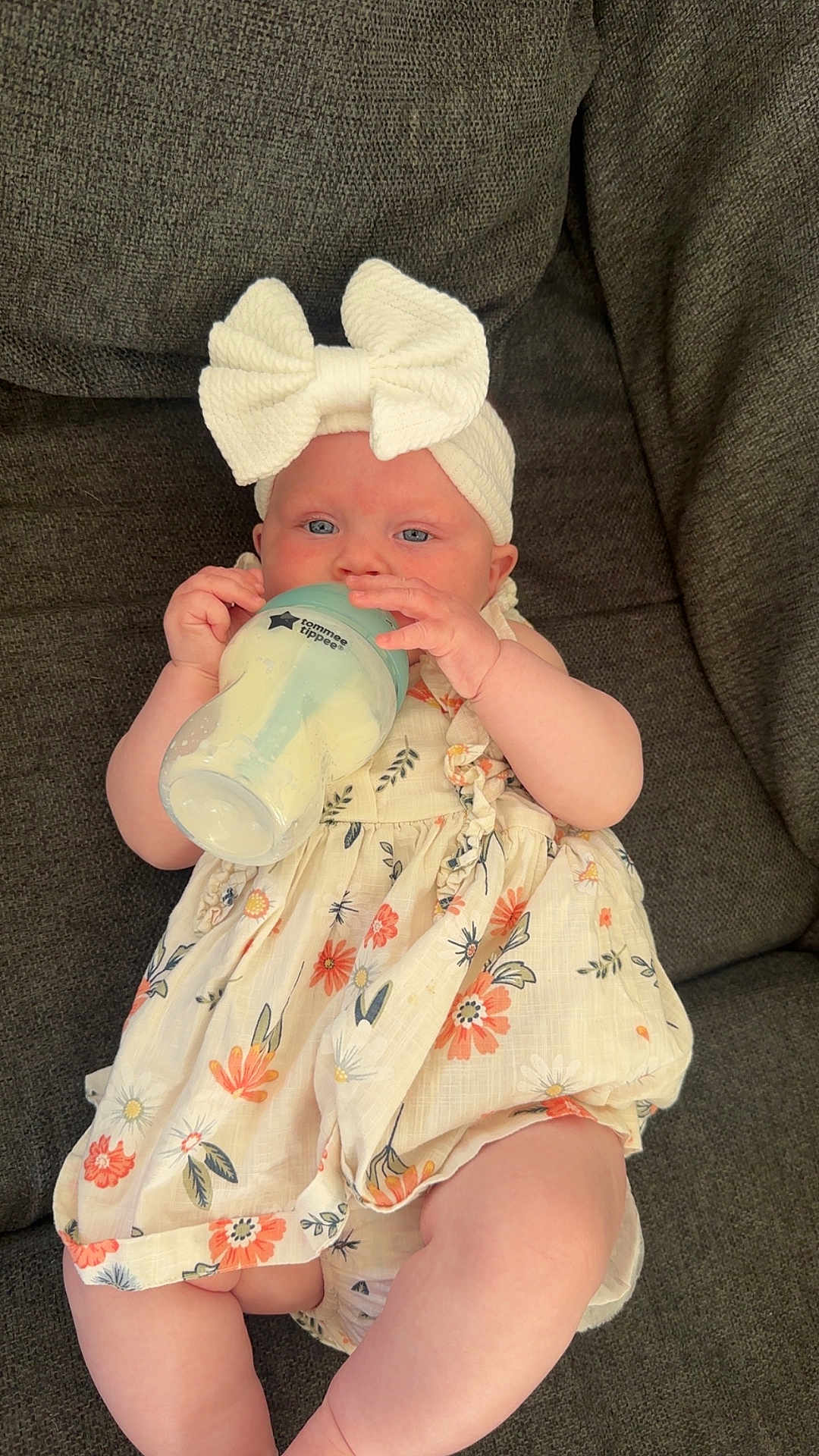 Aaliyah joined the competition — help win amazing prizes! baby, infant, bottle, milk, headband, bow, dress, floral, couch, fabric, cute, child, sitting, indoors, skin, person, feeding, comfort, young, relaxing