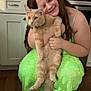 Thor is registered to the contest to win money with this photo: girl, cat, pet, smile, green_dress, kitchen, floor, cabinet, countertop, microwave, stove, long_hair, holding, orange_cat, fluffy, happy, indoor, wood_floor, female, cute