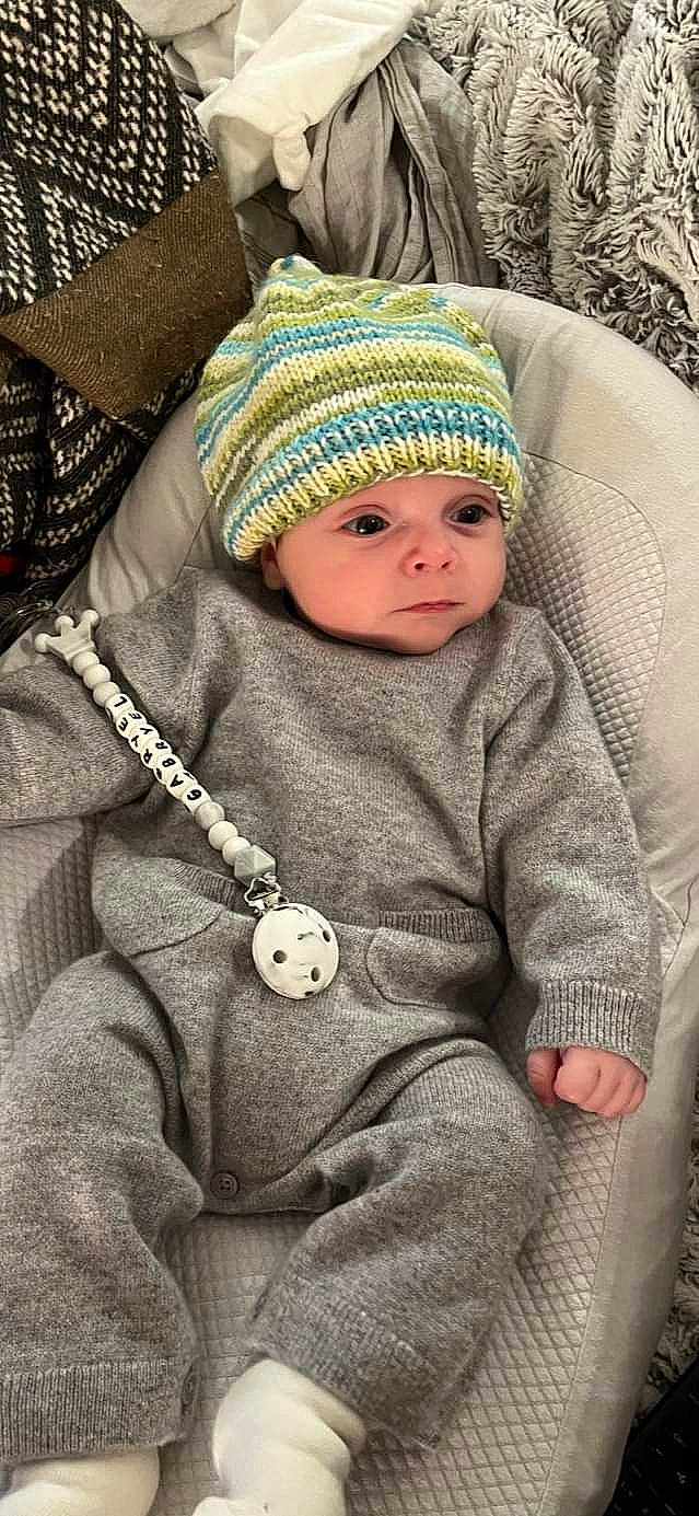 Gabryel a rejoint le concours — aidez-le/la à gagner de superbes lots ! baby, baby_toddler_clothing, beanie, cap, cheek, child, comfort, face, fashion_accessory, headgear, headwear, knit_cap, outerwear, person, sitting, skin, sleeve, textile, toddler, winter